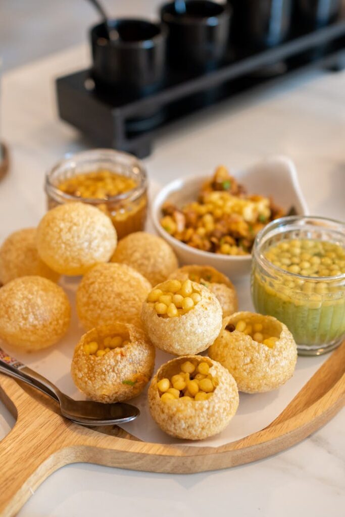 Delicious Indian street food Pani Puri served with spicy water and fillings on a wooden tray.